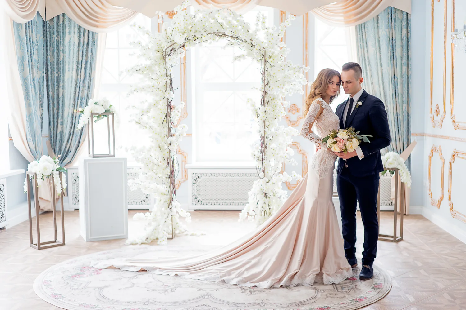 Newlywed couple in a bright ivory ballroom