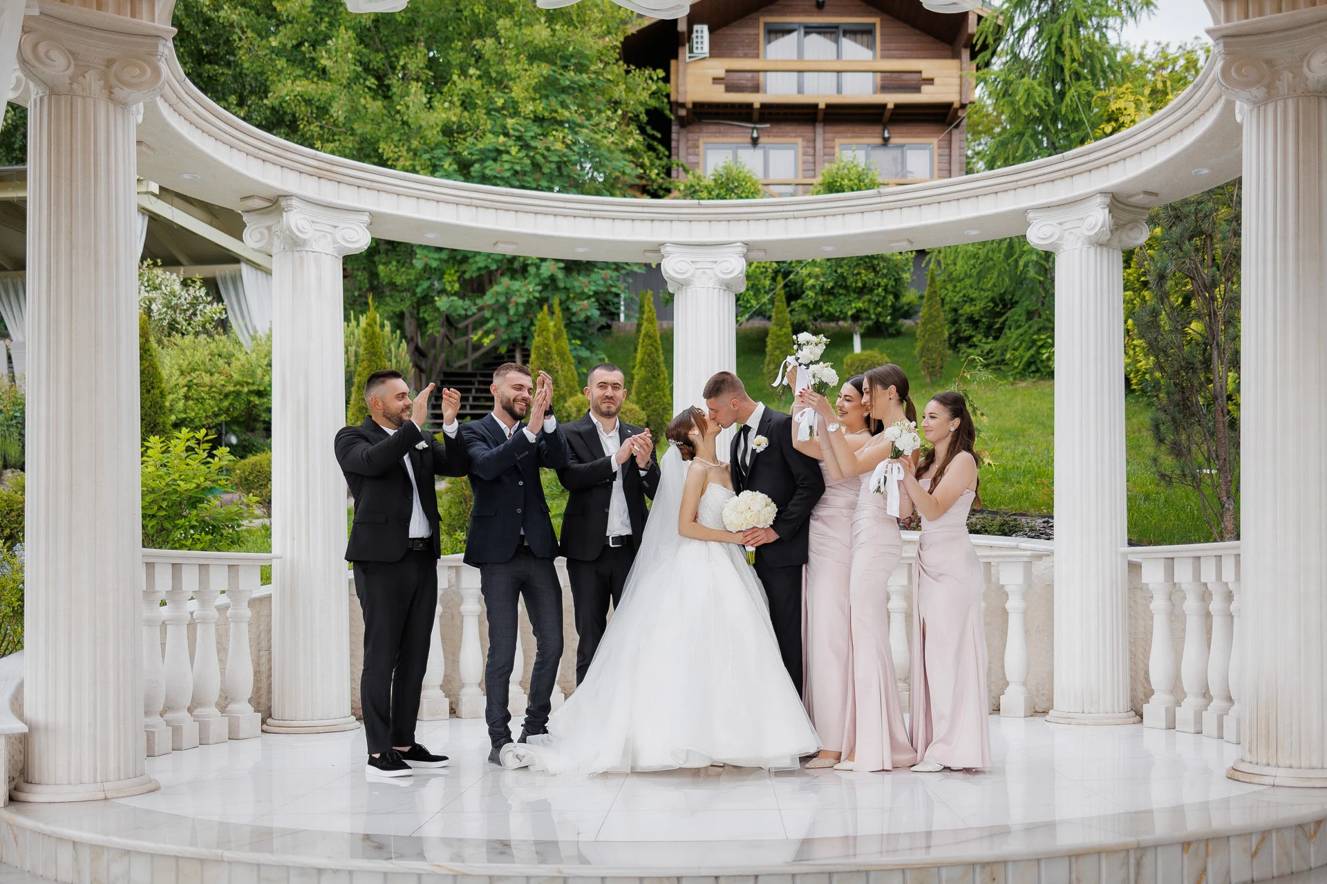A wedding party celebrating under a white garden colonnade